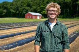 Eliudes营地Marcano, an exchange student from Puerto Rico, stands in a field at the Kingman 研究 Farm, where he helped support agricultural research at 主要研究 this past summer.